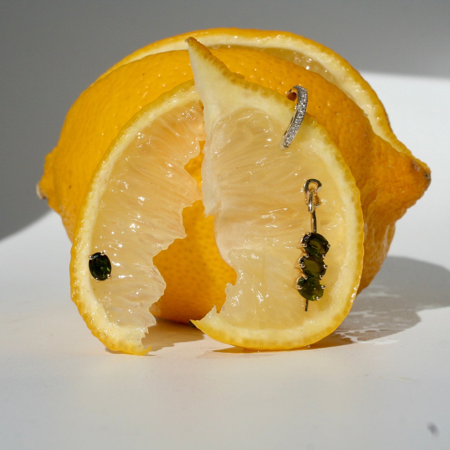 Sliced lemon with a earrings on a white surface